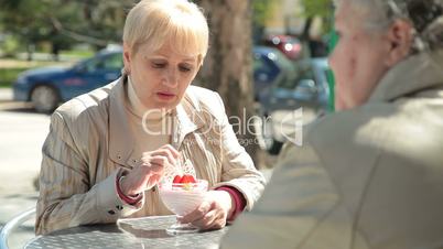 Senior Female Friends At Sidewalk Cafe