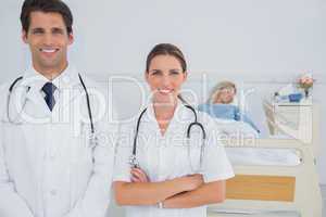 Two doctors standing in front of a hospitalized patient