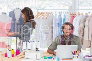 Fashion designer using laptop and smiling to the camera