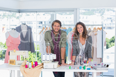 Smiling fashion designers leaning on desk