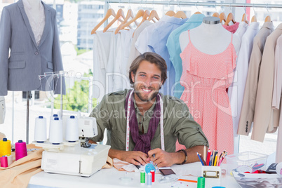Smiling fashion designer sitting behind a desk