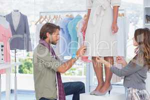 Fashion designers adjusting dress
