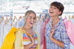 Two cheerful friends holding shopping bags