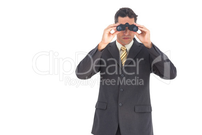 Businessman looking at the camera with binoculars