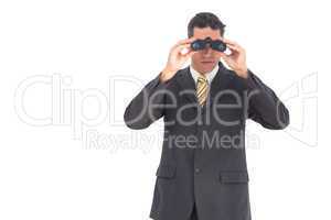 Businessman looking at the camera with binoculars