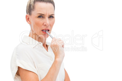 Concentrated businesswoman with pen on mouth