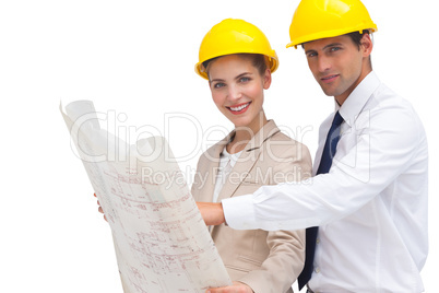Architects with construction plan and yellow helmets