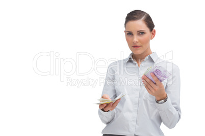 Businesswoman holding wads of cash and looking at camera