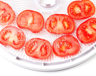 ripe tomato on food dehydrator tray, ready to dry