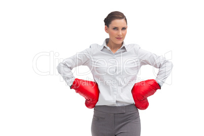 Businesswoman with hands on hips wearing boxing gloves