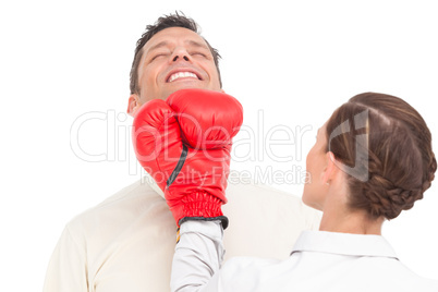 Businesswoman wearing boxing gloves punching businessman