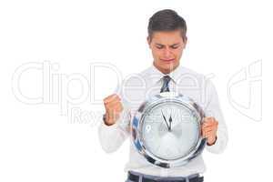 Nervous businessman holding and looking at clock