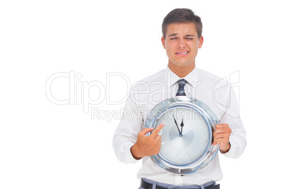 Worried businessman holding and pointing at clock