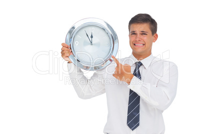 Anxious businessman holding and showing a clock