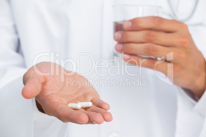 Doctor holding tablets and glass of water