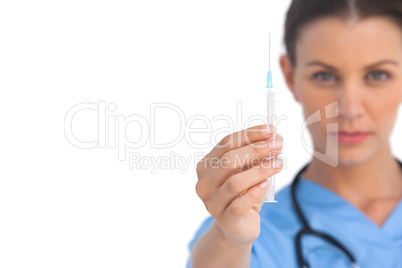 Serious surgeon holding up a syringe