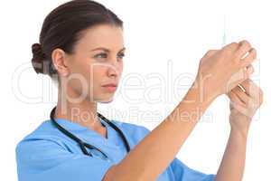 Serious surgeon holding up a syringe and checking it