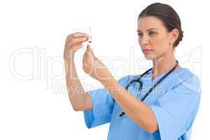 Serious surgeon holding up needle and checking it