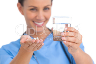 Smiling surgeon holding medicine and glass of water