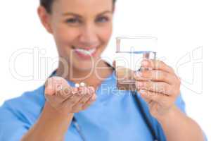 Smiling surgeon holding medicine and glass of water