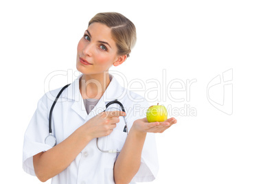 Smiling nurse pointing to green apple on her hand