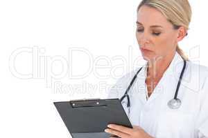 Doctor with stethoscope around her neck writing on clipboard