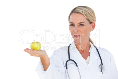 Smiling doctor holding apple and looking at camera