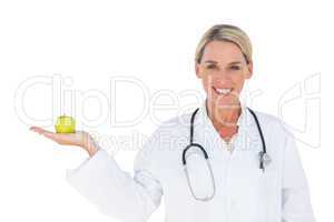 Happy doctor holding apple and looking at camera