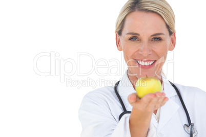 Happy doctor holding out apple and looking at camera