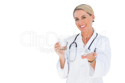 Happy doctor holding out pills and water glass