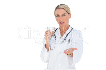 Stern doctor with medication and a glass of water in her hands