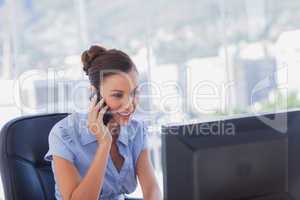 Happy businesswoman calling and working on her computer