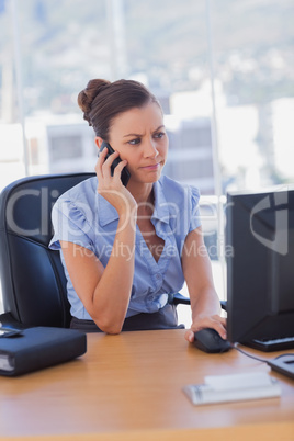 Concentrating businesswoman working on her computer and calling