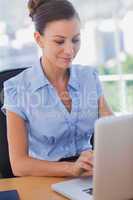 Happy businesswoman working on her laptop and smiling