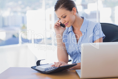 Happy businesswoman calling with her mobile phone and looking at