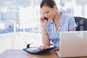 Happy businesswoman calling with her mobile phone and looking at