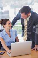 Happy business people smiling and working together with a laptop