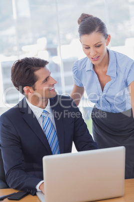Happy business people working together with a laptop and smiling