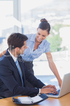 Happy business people working together with a laptop