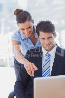 Businesswoman showing something on the laptop and smiling