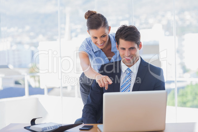 Businesswoman pointing to the laptop and smiling