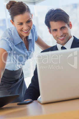 Business people looking the laptop and smiling