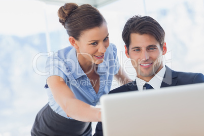 Happy business people looking together at the laptop