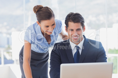 Happy business people looking at laptop and smiling