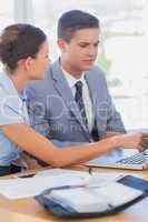 Smiling businesswoman showing partner something on a laptop