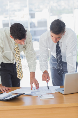 Serious businessmen working together leaning on the desk Serious businessmen working together leaning on the desk