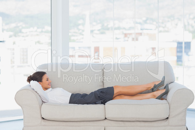 Smiling business woman lying down on the couch