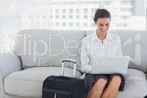 Businesswoman sitting on the couch using laptop