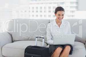 Happy businesswoman sitting on the couch using laptop