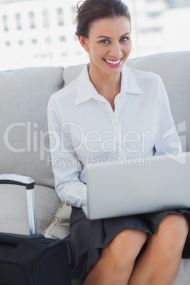 Businesswoman smiling at camera with laptop